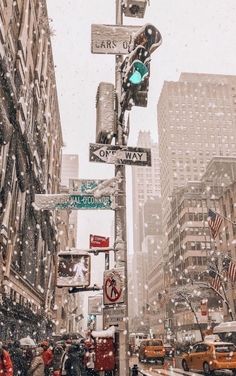 people walking down the street in front of tall buildings and traffic lights on a snowy day