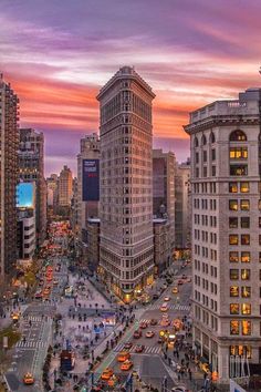 a city street filled with lots of traffic and tall buildings under a colorful sunset sky