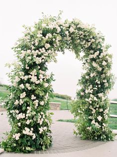 an arch covered in white flowers and greenery