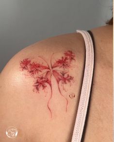 a woman's shoulder with red ink on it and flowers growing out of the back