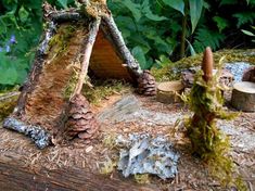 a small house made out of wood and mossy material with pine cones on the roof