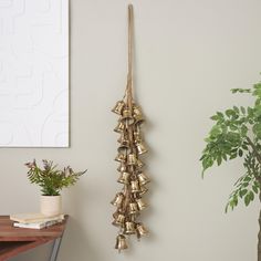 a wall hanging with bells on it next to a potted plant and a wooden table