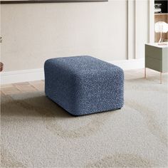 a blue ottoman sitting on top of a white carpeted floor next to a wall