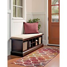 a wooden bench sitting on top of a floor next to a door with a red pillow