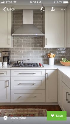 a kitchen with white cabinets and gray tile backsplash