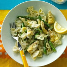 a white bowl filled with pasta and asparagus on top of a yellow table cloth