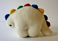 a white stuffed animal with multi colored spikes