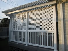 a white pergolated covered porch next to a brick wall and fenced in area