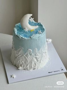 a blue and white cake with a moon on top