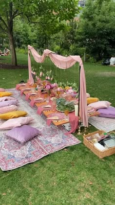 an outdoor picnic is set up in the grass with lots of pillows and blankets on it