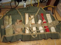 an army bag filled with various items on top of a wooden table next to wires and cords