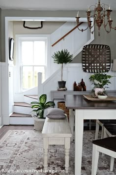 a dining room table with two chairs and a bench in front of the stairs that lead up to the second floor