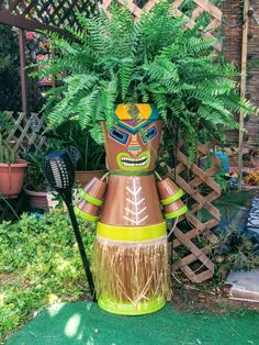 a planter made to look like a robot holding a broom and wearing sunglasses is in front of a garden