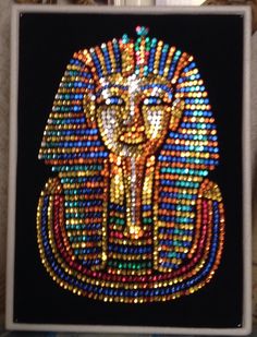 an egyptian pharaoh mask made out of multicolored beads and sequins on a black background