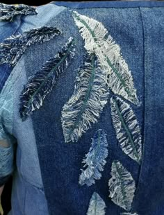 the back of a jean jacket with embroidered leaves on it