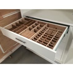 an open drawer with several compartments on the top and bottom, in a white cabinet