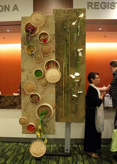 two people standing in front of a wall with baskets on it