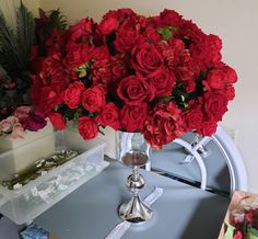 a vase filled with red roses sitting on top of a table next to other flowers