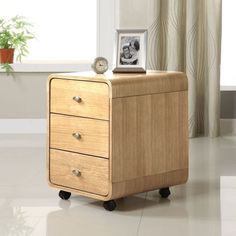 a wooden cabinet with two drawers and a clock on it's top, in front of a window