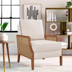 a white chair sitting in front of a window next to a table with a potted plant