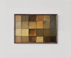 an abstract painting on the wall with multiple squares in brown and tan colors, hanging from a wooden frame