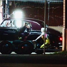 two women are riding in the back of an old car at night with their lights on