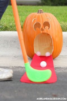 a person standing next to a fake pumpkin with its mouth open and tongue out on the ground