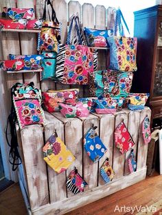 several purses and bags are on display in front of a wooden rack with shelves