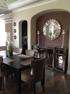 a dining room table with chairs and a mirror on the wall