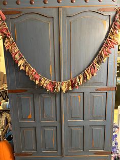 a blue armoire with fall decorations hanging from it