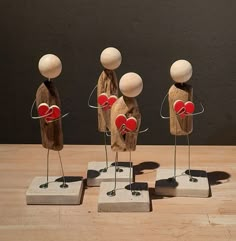 three wooden mannequins with red hearts in their hands