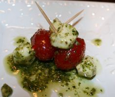 two strawberries on skewers covered in pesto and white sauce with toothpicks