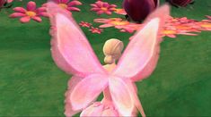 a pink fairy sitting on top of a lush green field