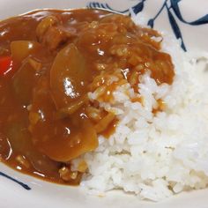 a white plate topped with rice and meat covered in gravy