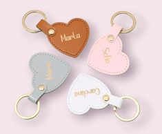 three leather key chains with personalized heart shaped tags on them, one is pink, the other is blue