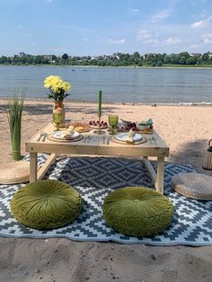 a picnic table set up on the beach with food and drinks in front of it