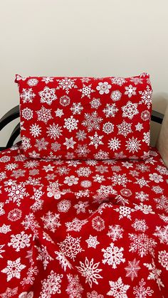 a bed with red and white snowflakes on it, next to a pillow