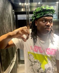 a man with dreadlocks and a green bandanna on his head standing in front of an elevator