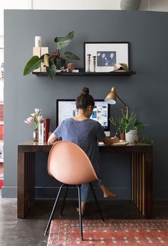 a woman sitting at a desk in front of a computer on top of a wooden table