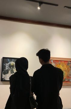 two people looking at artwork on display in an art gallery