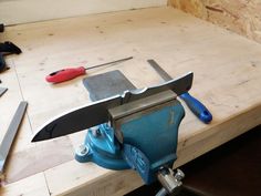 a bench with tools on top of it, including a vise and knife sharpener