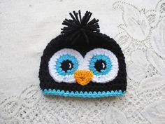 a crocheted penguin hat with blue eyes