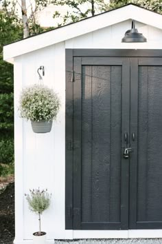 a black and white shed with two potted plants