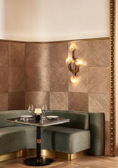 a corner table with two wine glasses on it in front of a wall that has geometric tiles