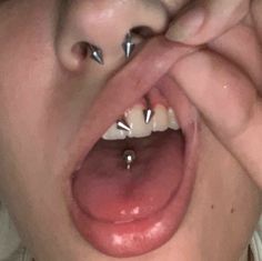 a woman with piercings on her tongue is making a funny face while holding her hand over her mouth