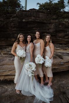 four bridesmaids pose for a photo in front of some rocks