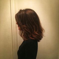 a woman standing in front of a white wall with her hair blowing back to the side