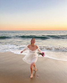 a woman in a white dress is running on the beach