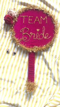 a pink sign that says team bride on it with some flowers in the corner next to it