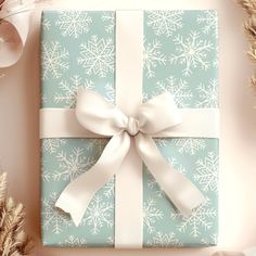 a present wrapped in blue and white paper with a bow on it, surrounded by feathers